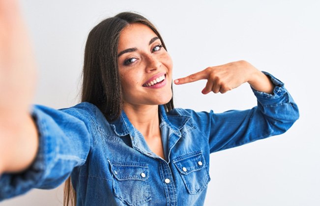 Smiling woman pointing to her white teeth